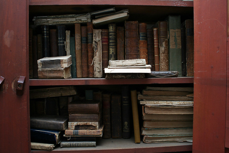 An old wooden cabinet with even older, tattered books inside.