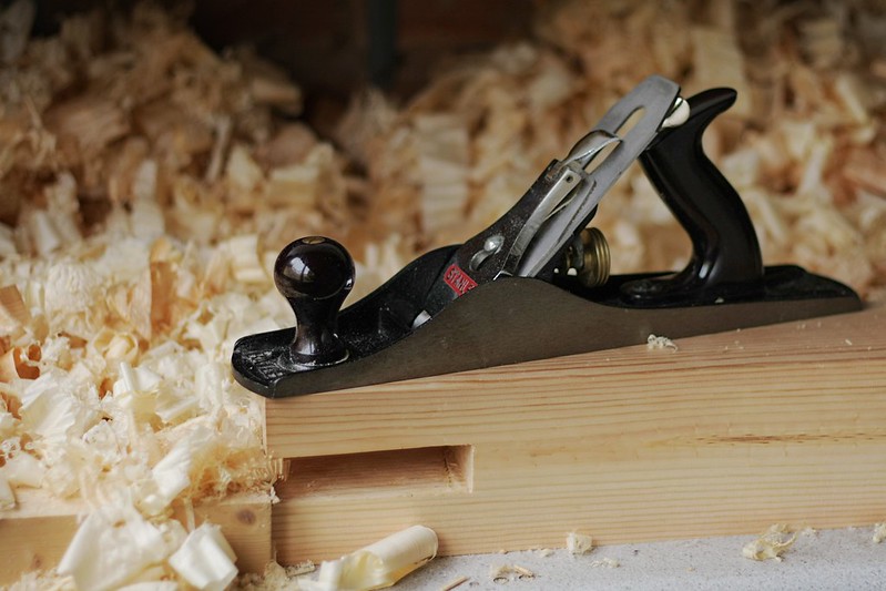 A wood plane with shavings in and around it. Credit: https://www.flickr.com/photos/73228447@N02/15225483531
